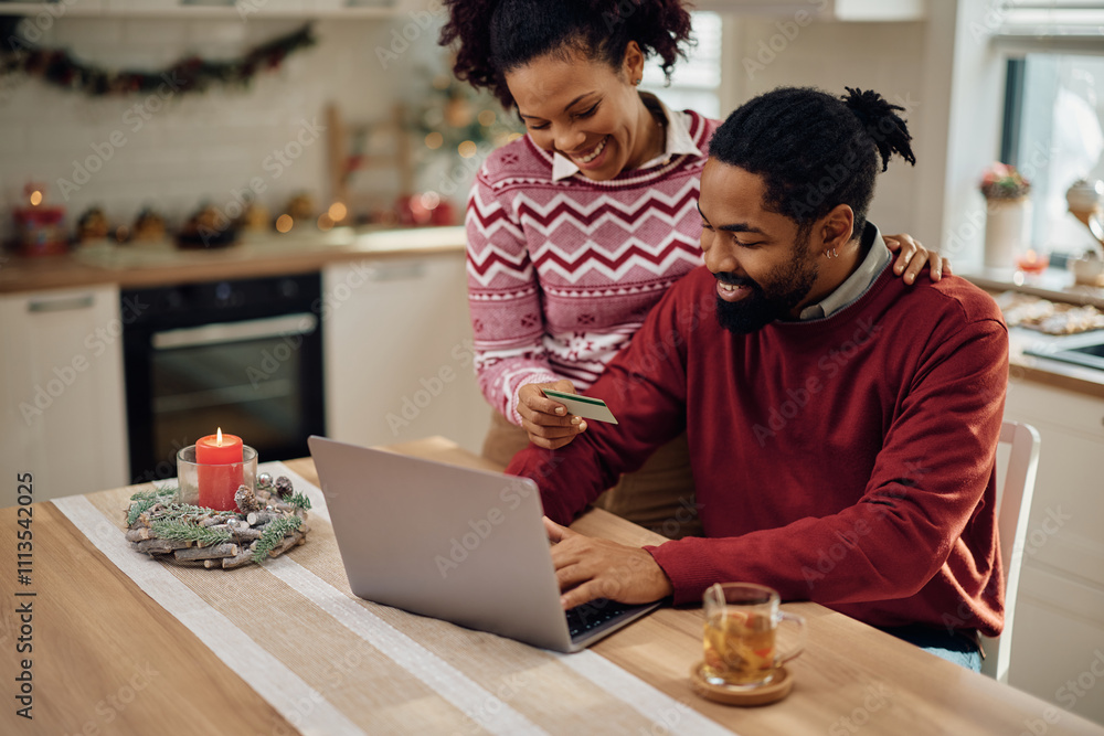Happy black couple using credit card while making online reservation for Christmas. Happy black couple using credit card while making online reservation for Christmas.