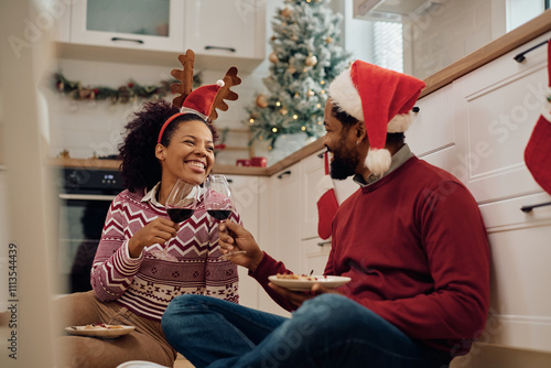 Happy African American couple toasting while eating Christmas cake at home. photo