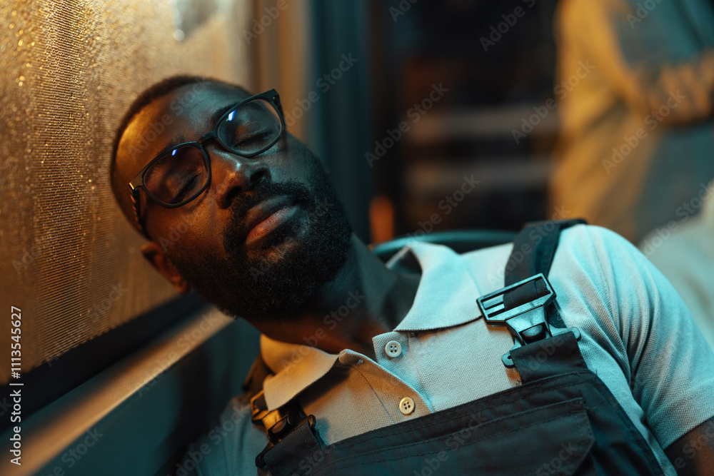 Obraz premium Young, black man in overalls sleeping on a bus