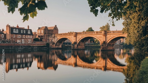 Beautiful bridge reflecting in calm water during golden hour in a quaint rive...