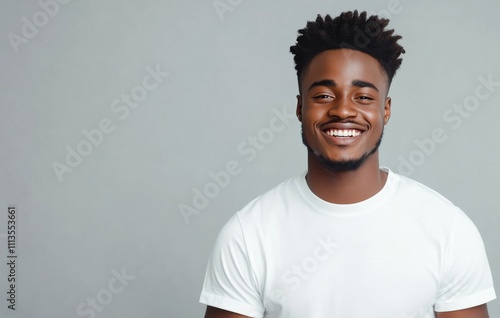 Smiling man in white t shirt poses against gray background showcasing confide...