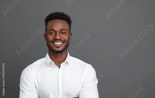 Smiling man dressed in white shirt with relaxed pose against gray background