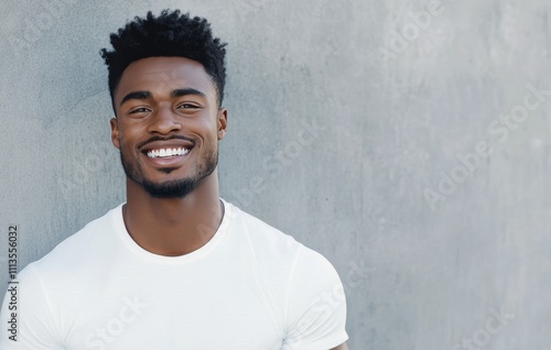 Smiling man in white t shirt poses against gray background showcasing confide...