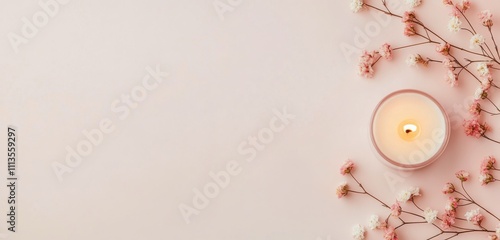 Delicate pink flowers and a lit candle create a calming atmosphere for relaxa...