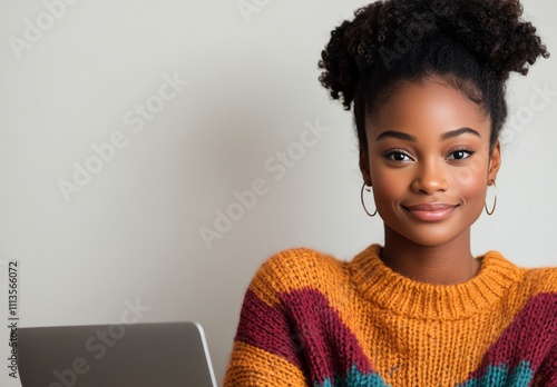 Young woman in cozy sweater smiles while working on laptop at home