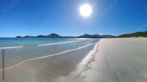 Tranquil beach scene with clear water and bright sun in blue sky