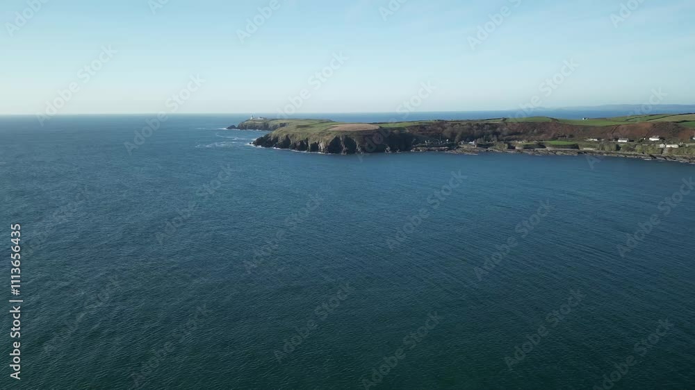 Distant headland in West Cork and wide calm Atlantic ocean on a sunny day, an aerial footage of a drone flying towards rugged, protruding coast in Ireland Distant headland in West Cork and wide calm Atlantic ocean on a sunny day, an aerial footage of a drone flying towards rugged, protruding coast in Ireland