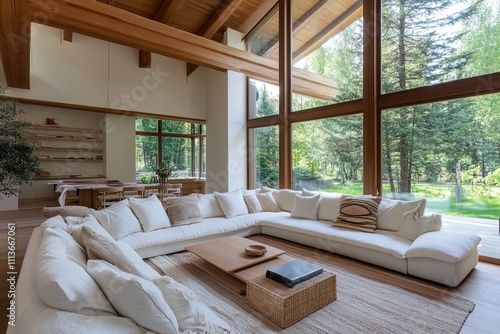 Modern living room with large windows showcasing a serene forest view and cozy seating arrangement