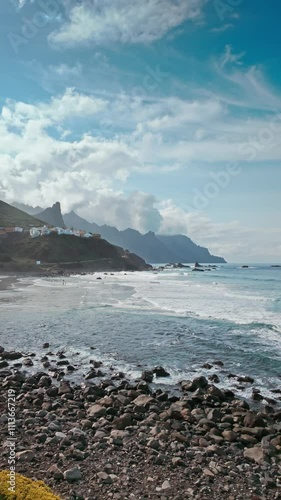 Crashing ocean waves against a rugged rocky beach under a bright blue sky