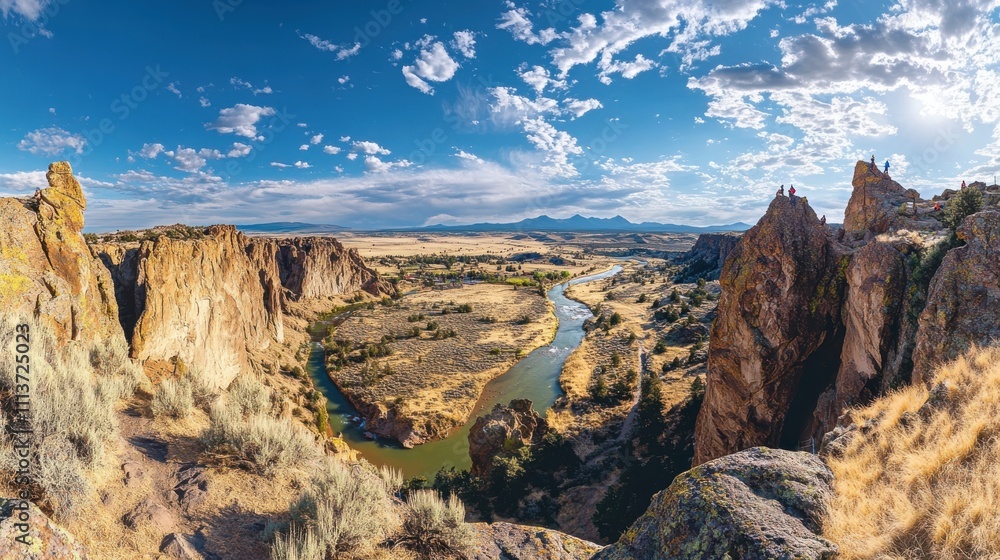 Obraz premium The panorama showcases the dramatic cliffs and vibrant landscape of Smith Rock State Park, featuring the Crooked River meandering through lush terrain under a brilliant sky.