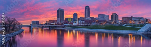 The beautiful Des Moines skyline glows under a colorful sunset, with reflections shimmering on the river's surface, creating a tranquil urban atmosphere. photo