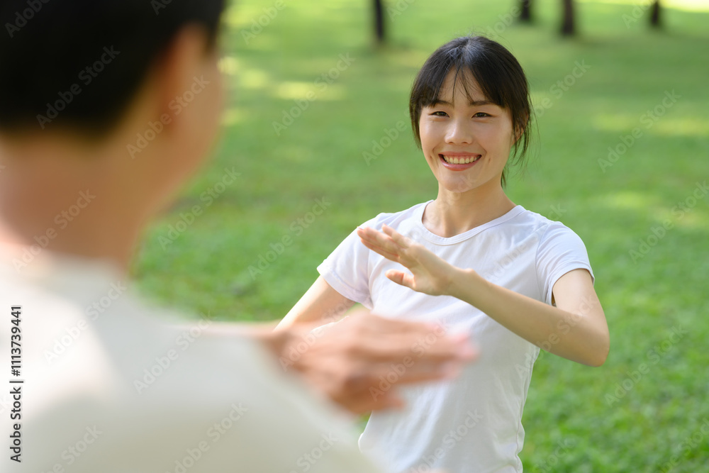 Cheerful asian woman and father practicing Tai Chi in the park. Healthy and outdoor activity concept Cheerful asian woman and father practicing Tai Chi in the park. Healthy and outdoor activity concept