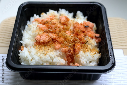 Salmon flake and sesame seeds furikake rice in square black plastic box.