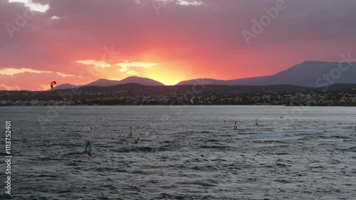 Surfers on a windy day at a colorful sunset in Artemida, Greece