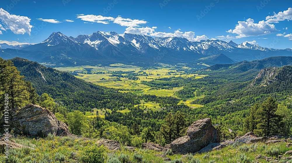Panoramic view of a valley nestled between snow-capped mountains under a vibrant blue sky. Panoramic view of a valley nestled between snow-capped mountains under a vibrant blue sky.