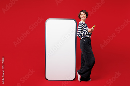 Foto Full body young happy woman wear blue striped sweatshirt casual clothes big huge blank screen mobile cell phone with workspace copy space mockup area use smartphone isolated on plain red background