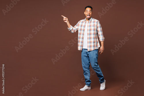 Full body young man of African American ethnicity he wear blue shirt casual clothes walk go point index finger on empty blank area isolated on plain brown background studio portrait Lifestyle concept