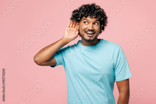 Young curious nosy happy Indian man he wear blue t-shirt casual clothes try to hear you overhear listening intently isolated on plain pastel light pink background studio portrait. Lifestyle concept. photo