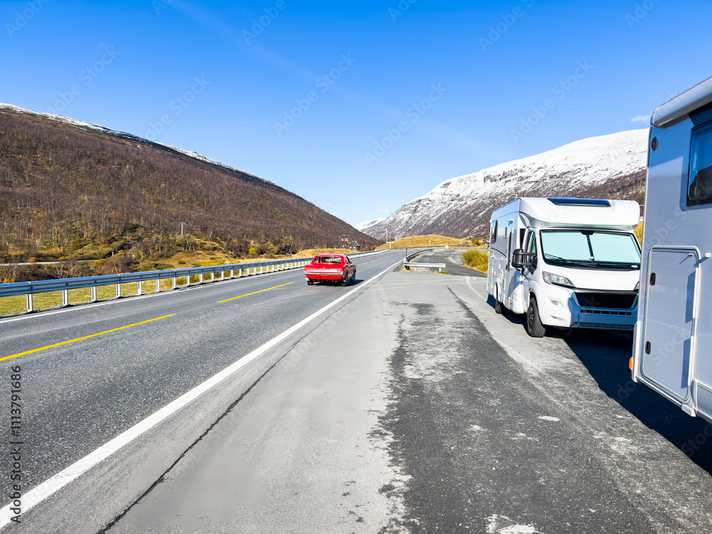 White camper van parked on roadside viewpoint overlooking scenic mountain road with red sports car driving away White camper van parked on roadside viewpoint overlooking scenic mountain road with red sports car driving away