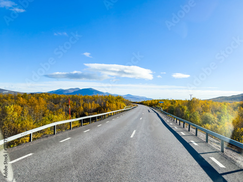 Motorhome driving on a scenic road in Kiruna, Sweden, with autumn foliage and beautiful lake views. photo