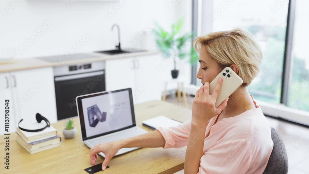Caucasian woman ordering clothes online using phone and laptop. She browses delivery website and makes payment with bank credit card. Ideal for e-commerce and online shopping concepts. Caucasian woman ordering clothes online using phone and laptop. She browses delivery website and makes payment with bank credit card. Ideal for e-commerce and online shopping concepts.
