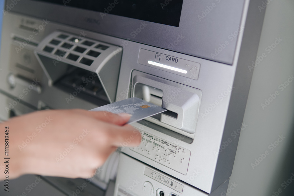 Close up picture of a person using ATM, inserting card to the machine before withdrawing money. Close up picture of a person using ATM, inserting card to the machine before withdrawing money.