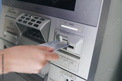 Close up picture of a person using ATM, inserting card to the machine before withdrawing money. photo