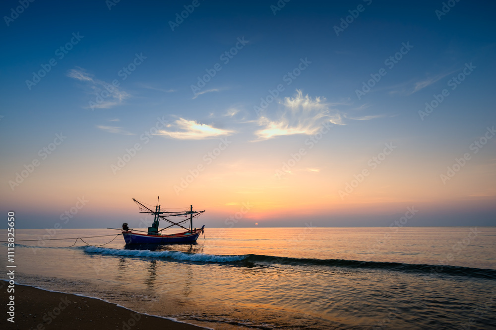 Sunrise on the sea beach with fishing boat