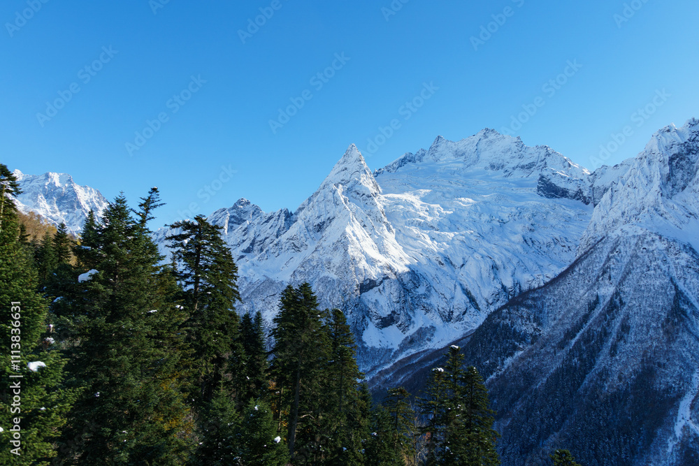 Fototapeta premium Picturesque landscape in Dombay with amazing snow-capped peaks and majestic blue slopes of North Caucasus Mountains. Mountain ski resort in Karachay-Cherkessia, Russia