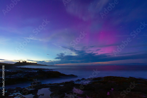 Silhouette of Dunstanburgh Castle with a spectacular Aurora above. Northumberland, England, UK. photo