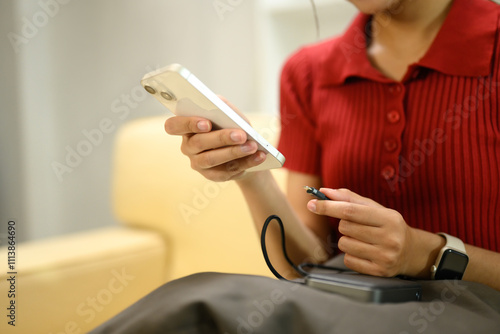 Young woman charging smartphone with portable power bank