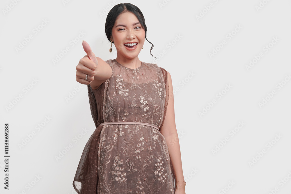 Cute young Asian woman in a brown dress smiling and showing a thumb up gesture. Cute young Asian woman in a brown dress smiling and showing a thumb up gesture.