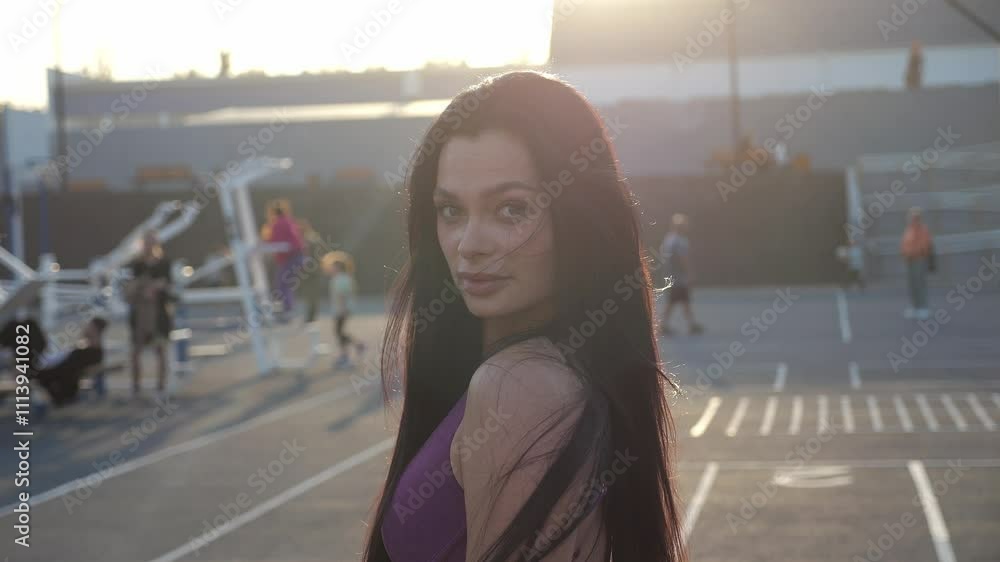 Portrait of a slender athletic brunette with long hair on a sports field with outdoor exercise equipment. A woman in sexy sportswear on a modernly equipped sports field at the sunset of summer. Portrait of a slender athletic brunette with long hair on a sports field with outdoor exercise equipment. A woman in sexy sportswear on a modernly equipped sports field at the sunset of summer.