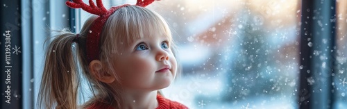 Little Girl Watching Snowfall Through Window with Reindeer Antlers