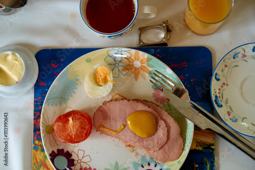 Overhead view of a colorful breakfast plate with eggs, ham, tomato, accompanied by a cup of coffee and an orange juice, Scotland photo