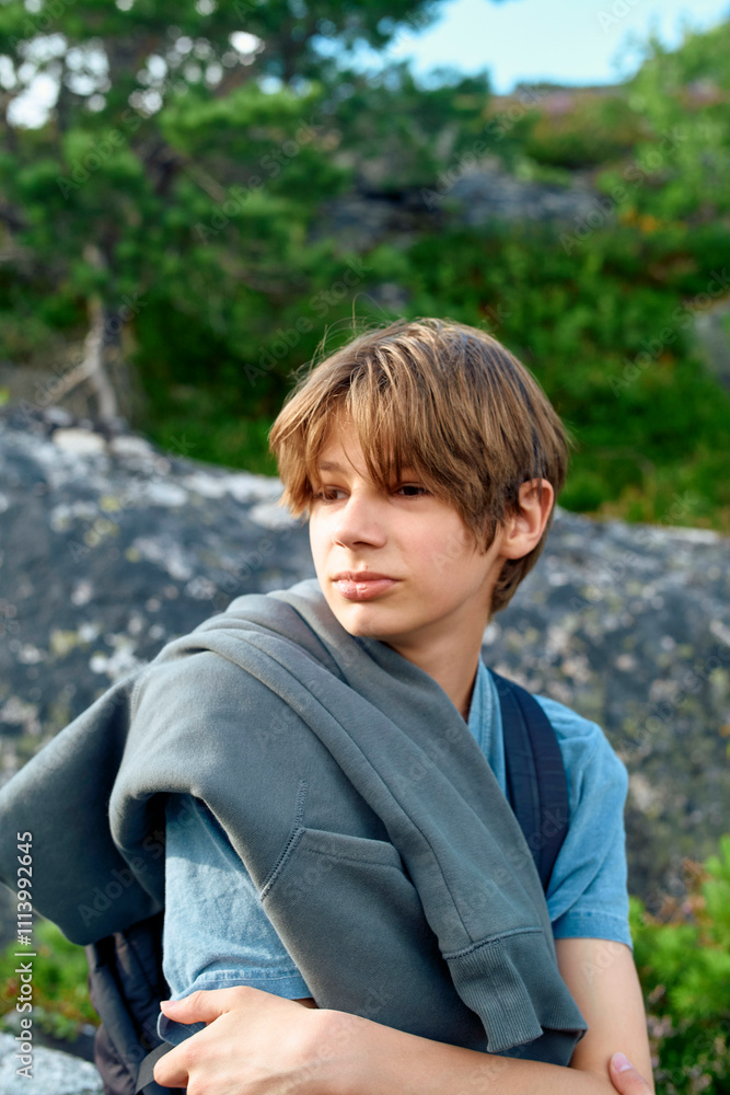Young teenager holding a jacket over his shoulder outdoors during a hike with a rocky background, Romsdalfjorden, Norway Young teenager holding a jacket over his shoulder outdoors during a hike with a rocky background, Romsdalfjorden, Norway