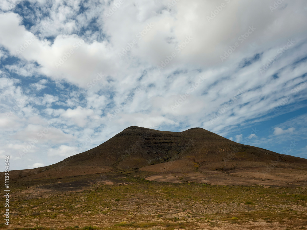 A solitary volcano under a sky scattered with white clouds, Fuerteventura, Spain A solitary volcano under a sky scattered with white clouds, Fuerteventura, Spain