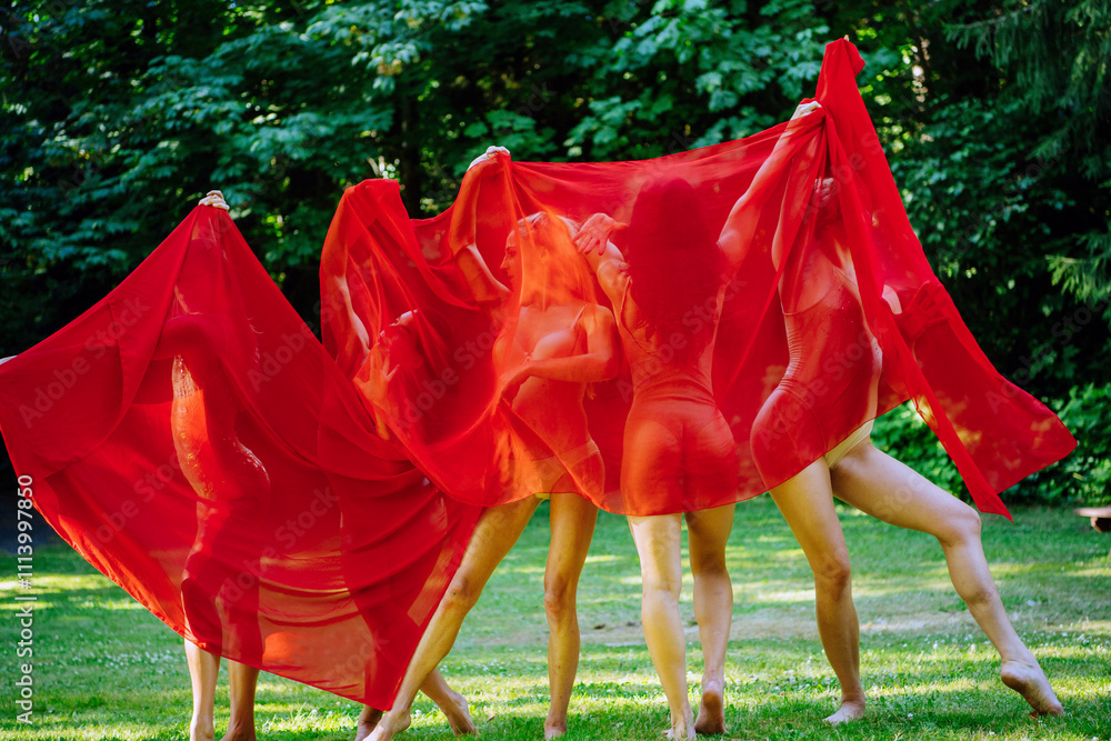© Connect Images - A playful group of 4 dancers shrouded in a billowing red fabric outdoors, expressing a sense of freedom and creativity, USA