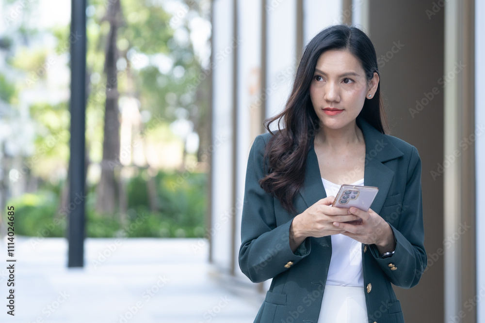 Asian businesswoman using phone urban setting lifestyle content bright day professional concept