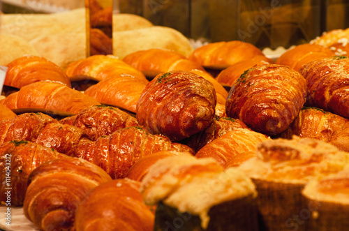 croissants in cafe shop.Bakery with fresh bread behind glass with chef putting out freshly baked buns photo