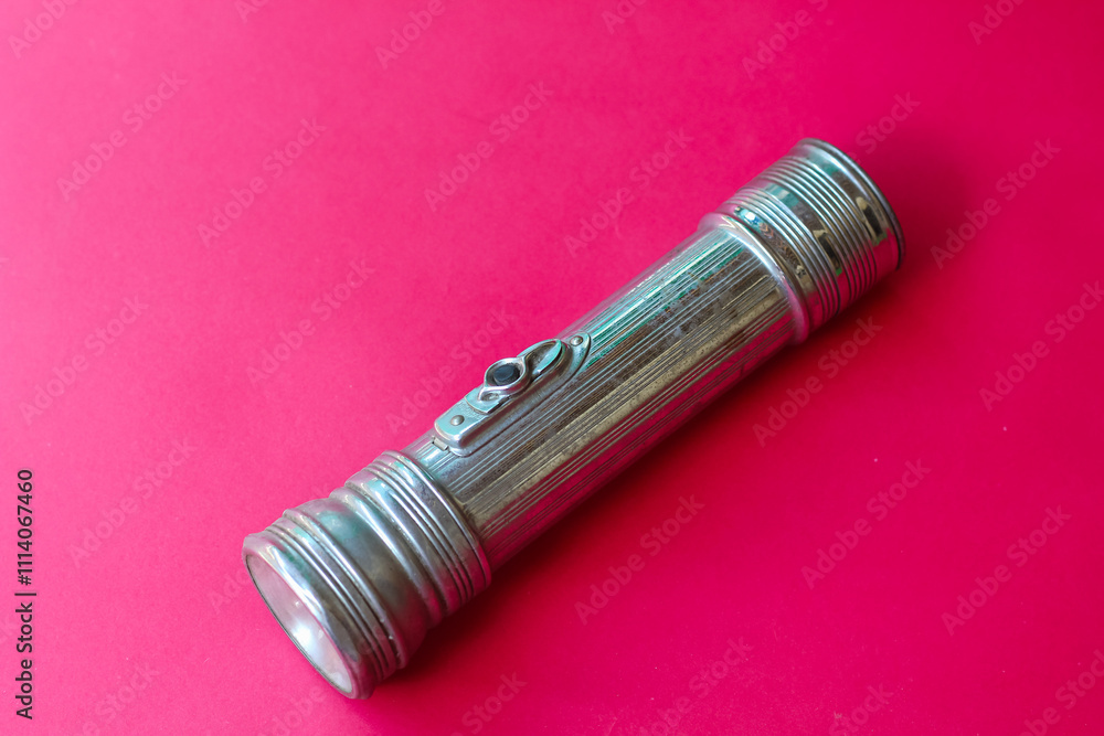 old iron flashlight isolated on red background old iron flashlight isolated on red background
