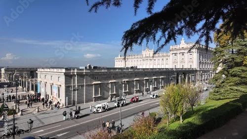 Almudena Cathedral surrounded by greenery, with tourists walking nearby on a sunny day in Madrid.
