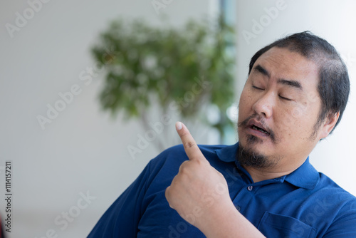 Canvas Print Middle aged asian man pointing up to blank space, excited and surprised expressi