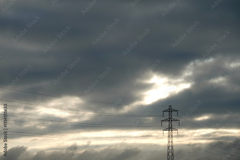 Pylônes électriques dans un paysage de campagne sous un ciel orageux Pylônes électriques dans un paysage de campagne sous un ciel orageux
