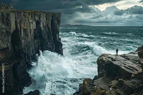 A person stands on rocky cliffs as waves crash below during dusk