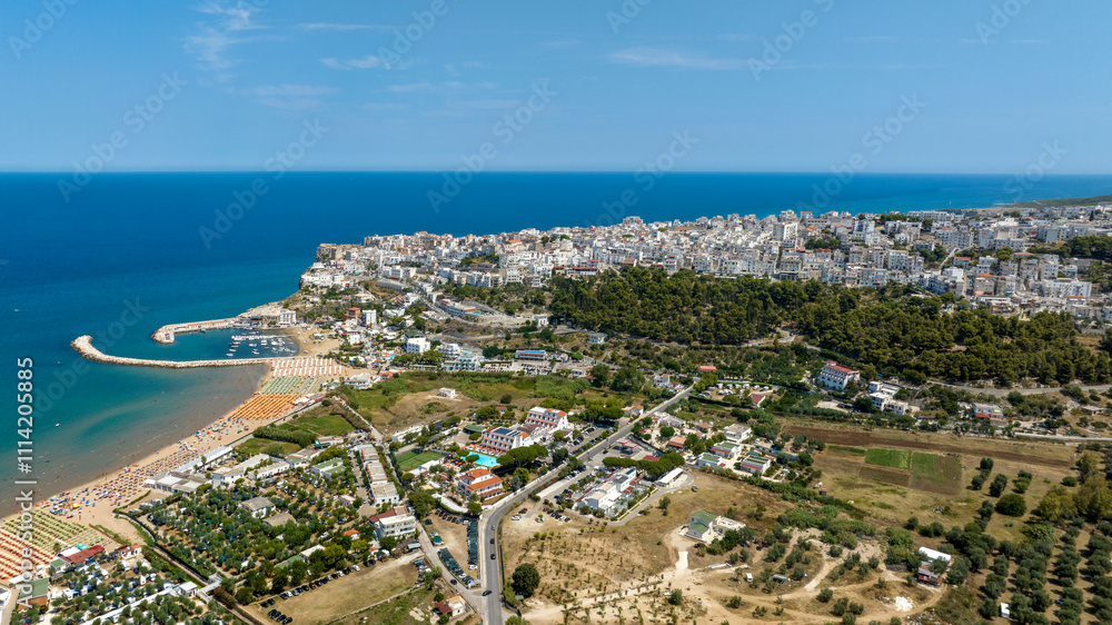 Obraz premium Aerial view of the town, marina and beach of Peschici, located in Puglia, Italy, on the coast of the Adriatic Sea. It is a tourist destination in Gargano, in the province of Foggia.