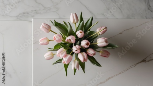 Delicate pink tulip bouquet arranged on a light marble backdrop creating a serene and elegant floral composition from an overhead perspective. photo