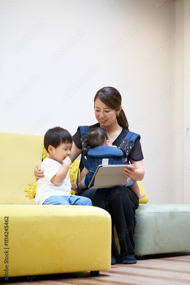 ソファに座ってタブレットPCの画面を見る親子
