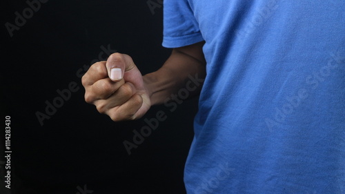 Man showing clenched fist in aggression concept photo, black background