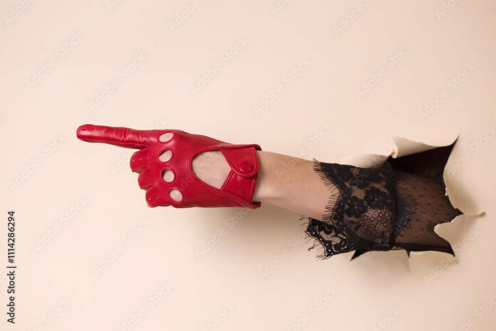 A woman's hand in a leather glove is pointing with her index finger